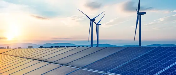 夕日に照らされたソーラーパネルと風力発電タービン