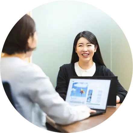 ノートPCを開きながら笑顔で対話する2人の女性社員
