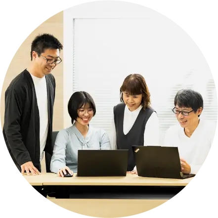 ノートPCを囲んで和やかに話し合う4人の社員