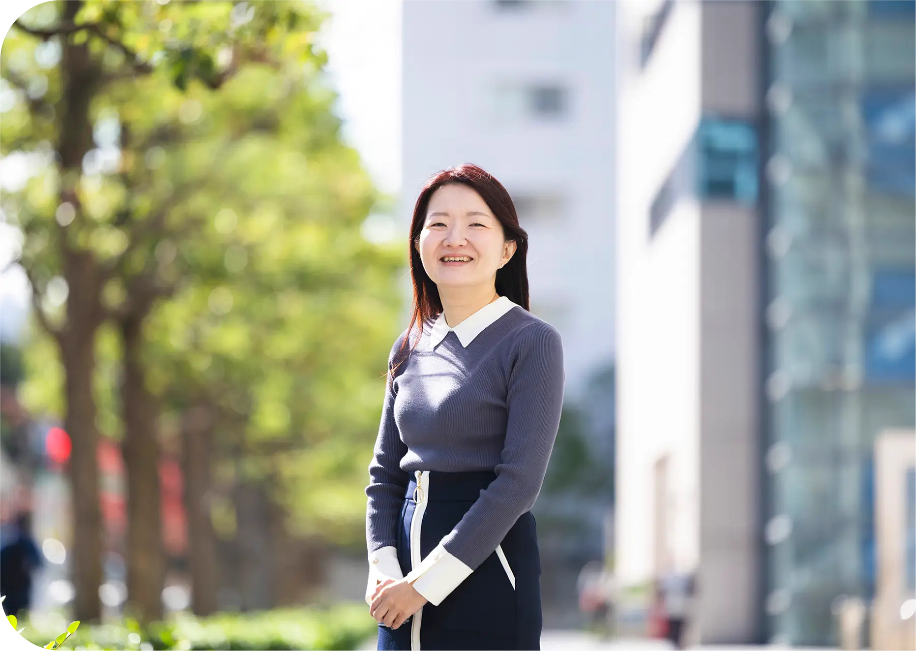 緑の木々を背景に屋外で笑顔のH.Kのポートレート