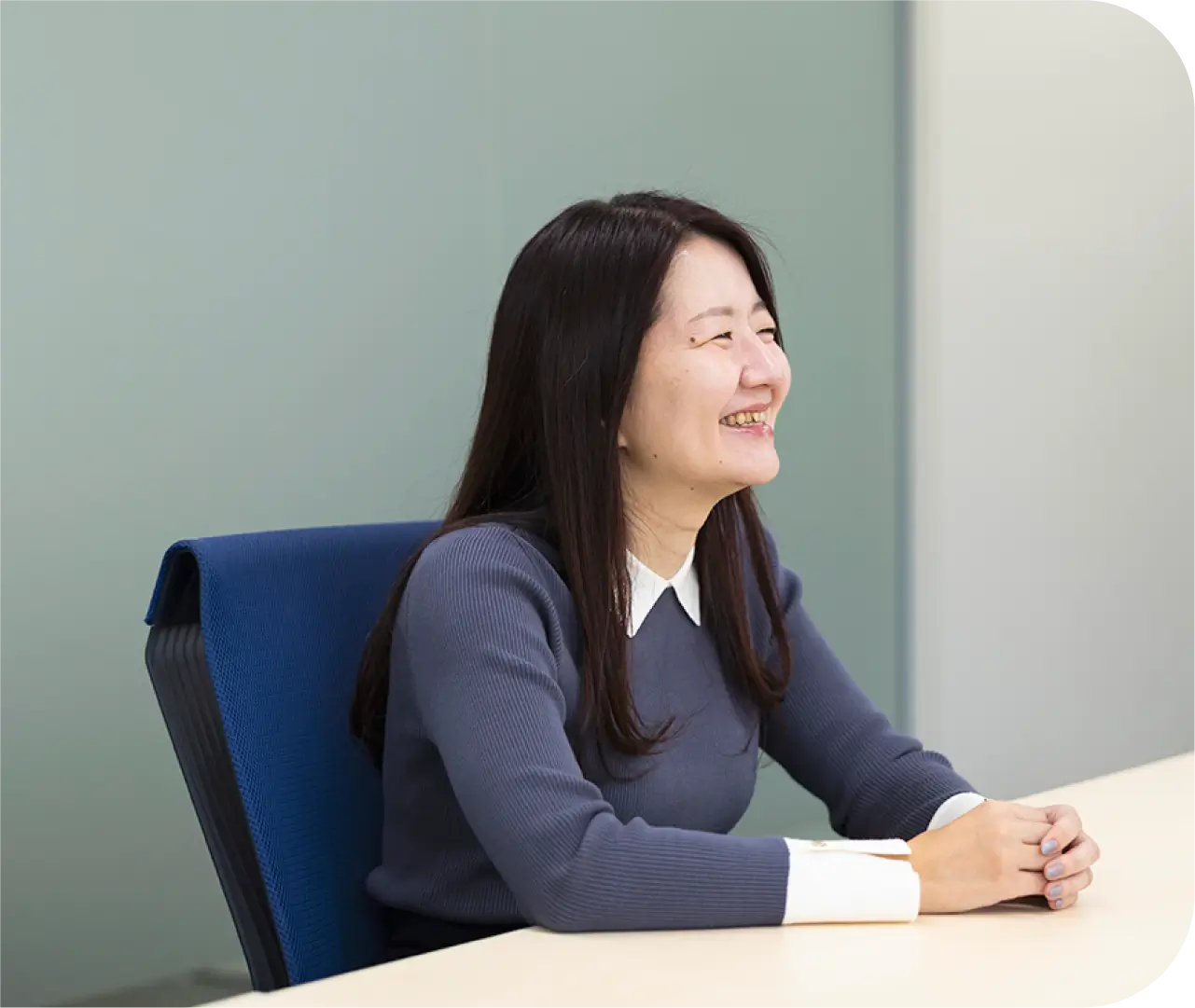 会議室の椅子に座り笑顔で語るH.K