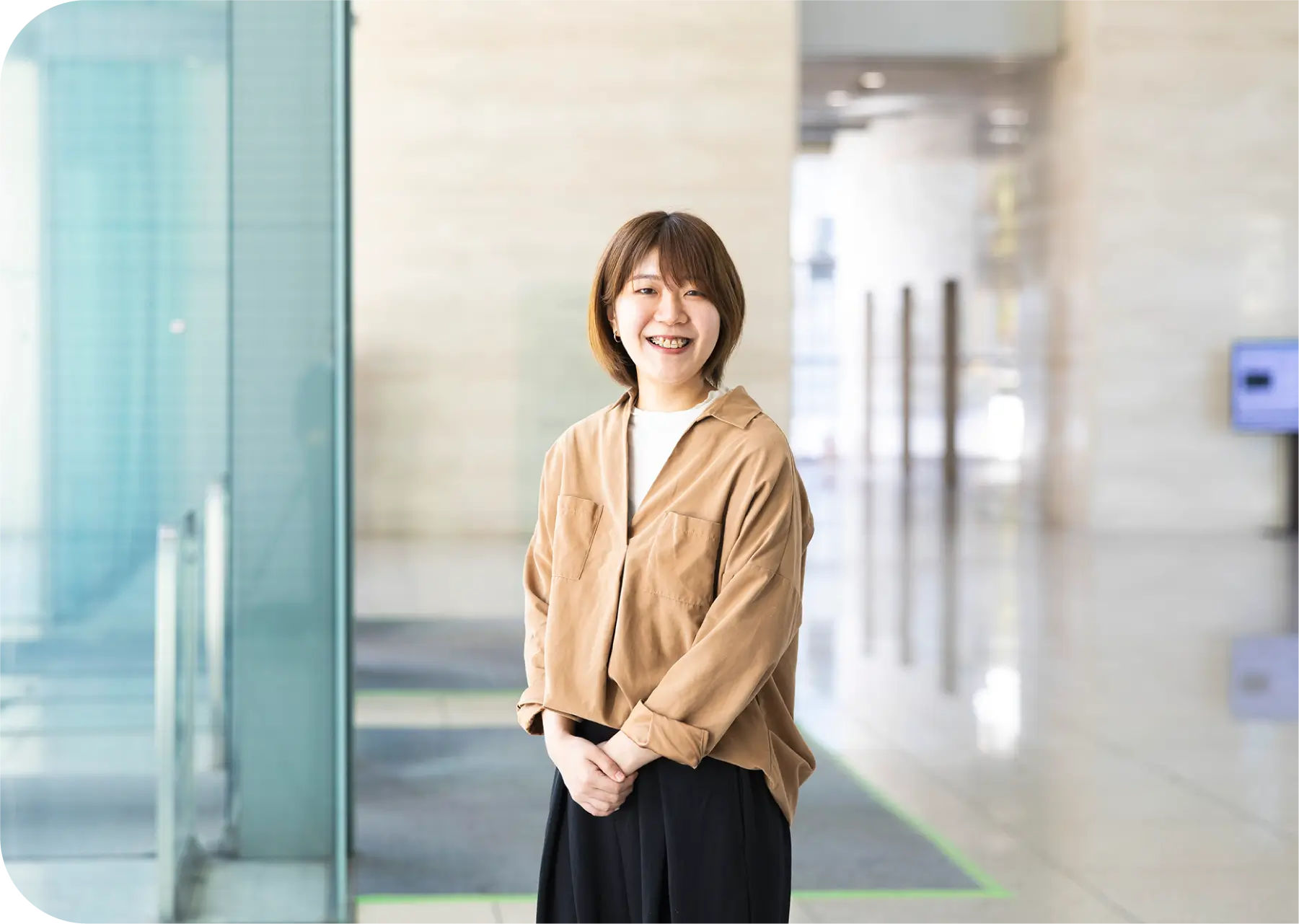 ビルのエントランスホールで笑顔のS.Hのポートレート