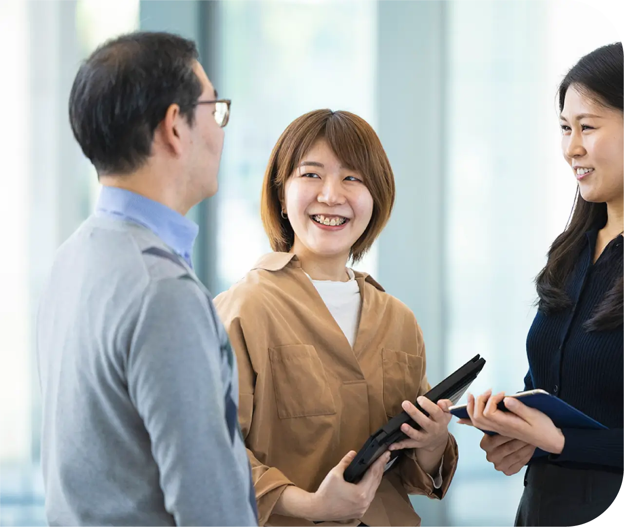 タブレットを手に同僚2人と立ち話をするS.H