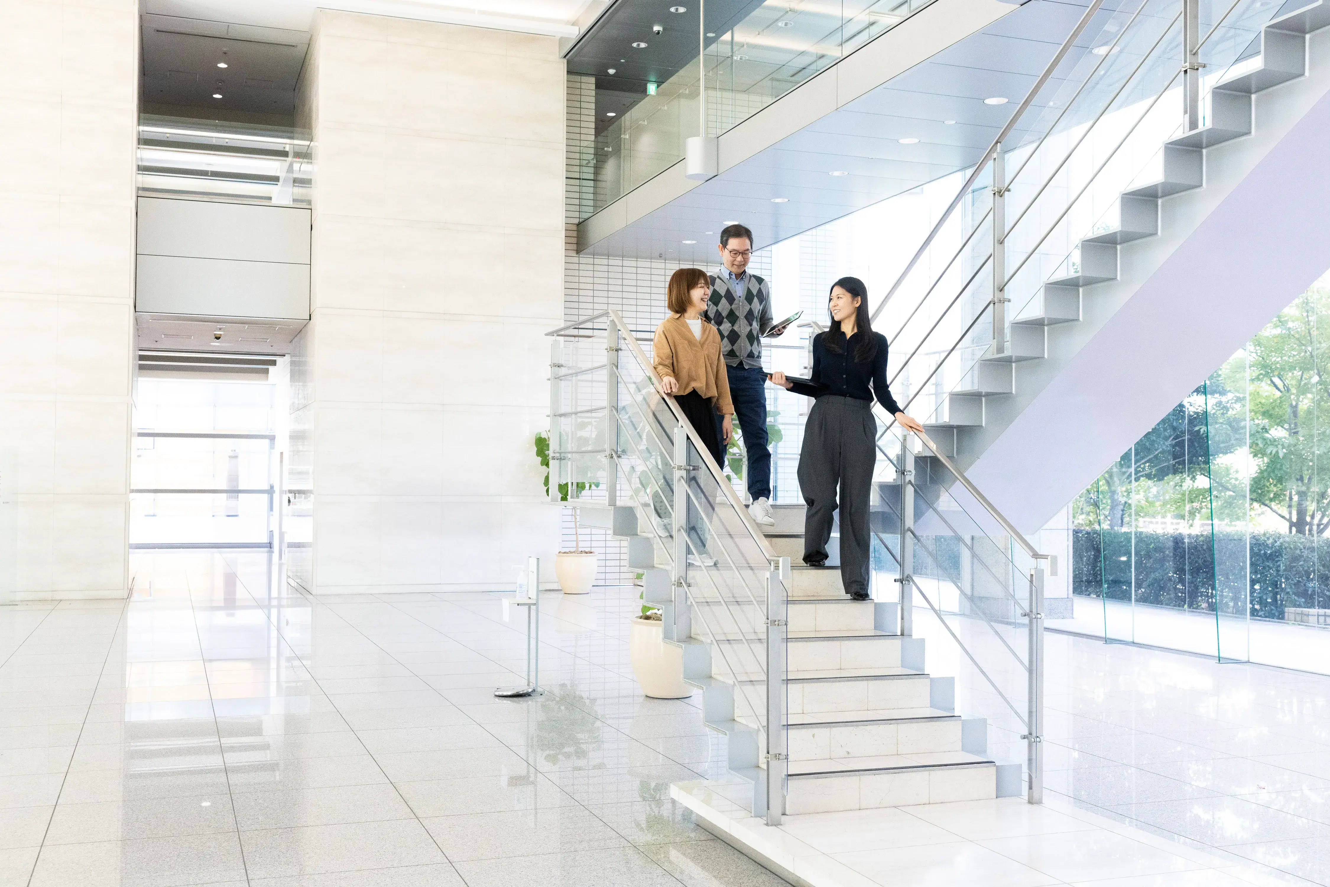 オフィスビルの開放的な階段を歩く社員たち