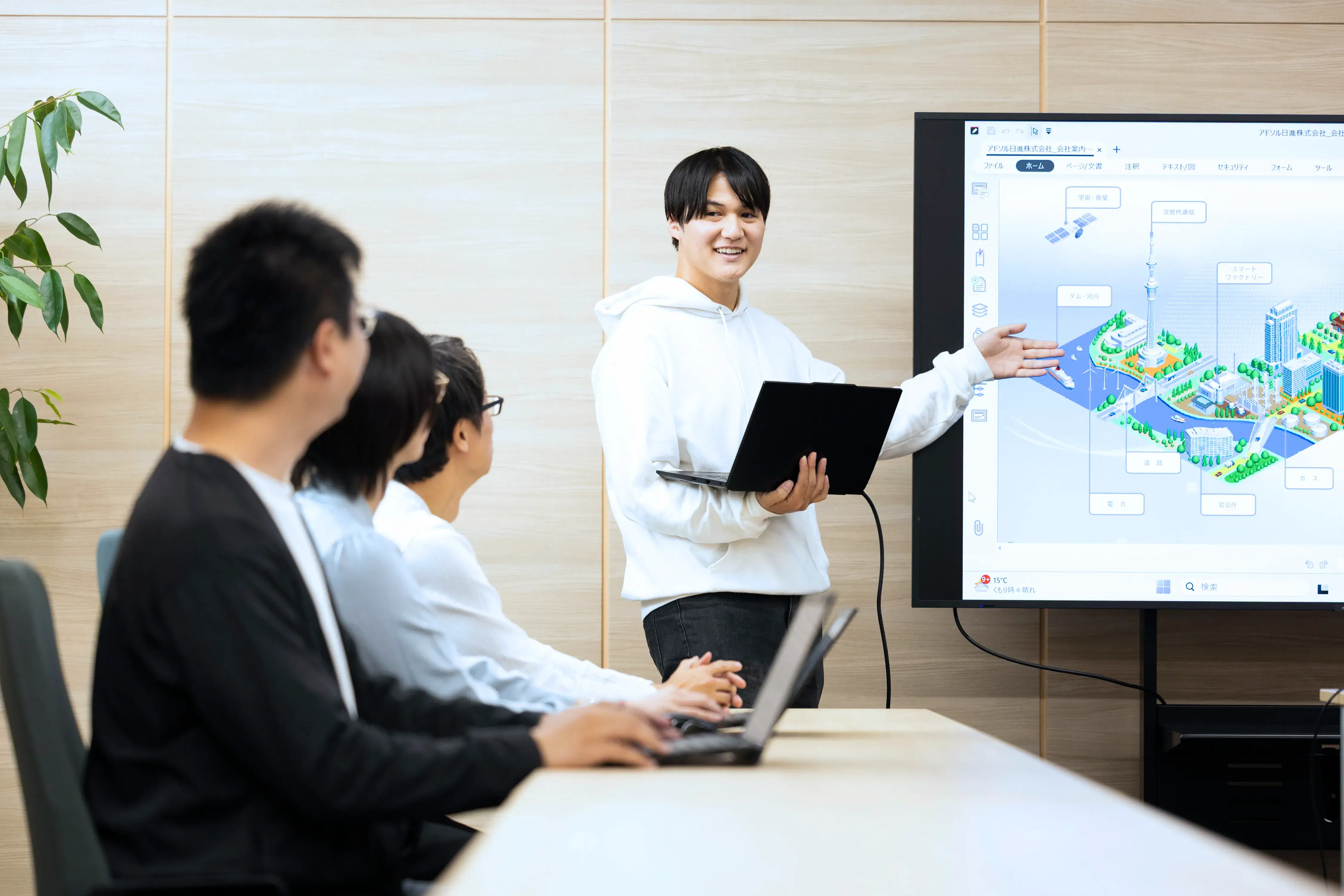 大型モニターでプレゼンテーションをする社員